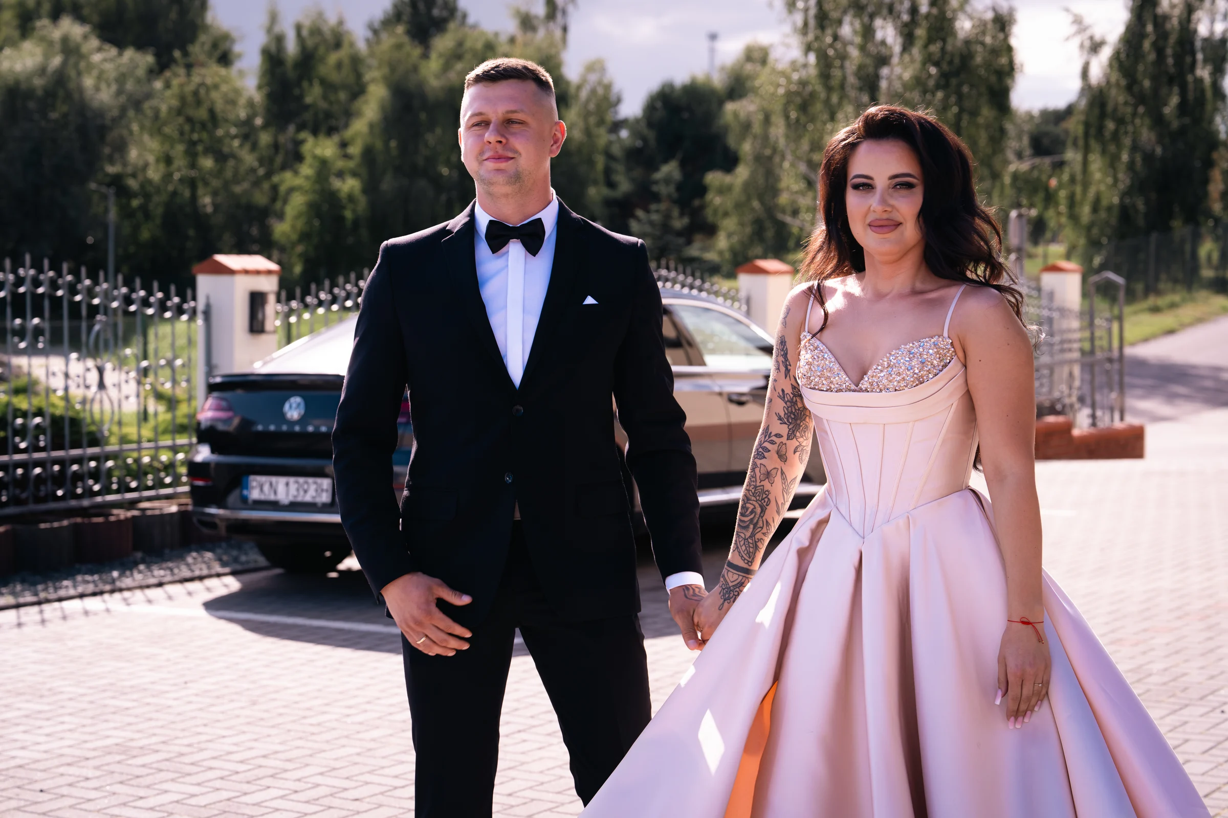 Para trzyma się za ręce obok samochodu