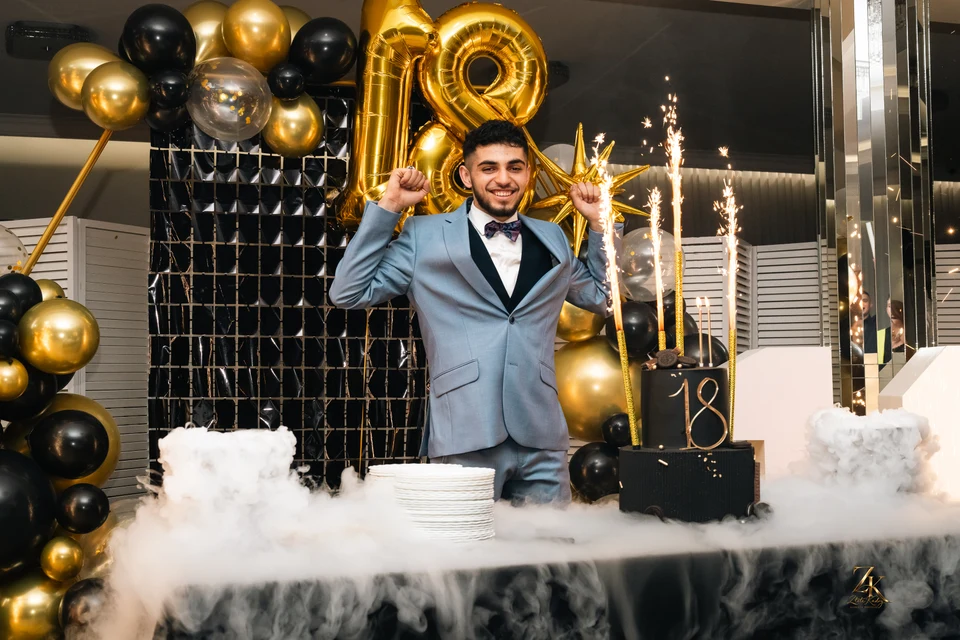 Nataniel przy torcie na tle złotych balonów